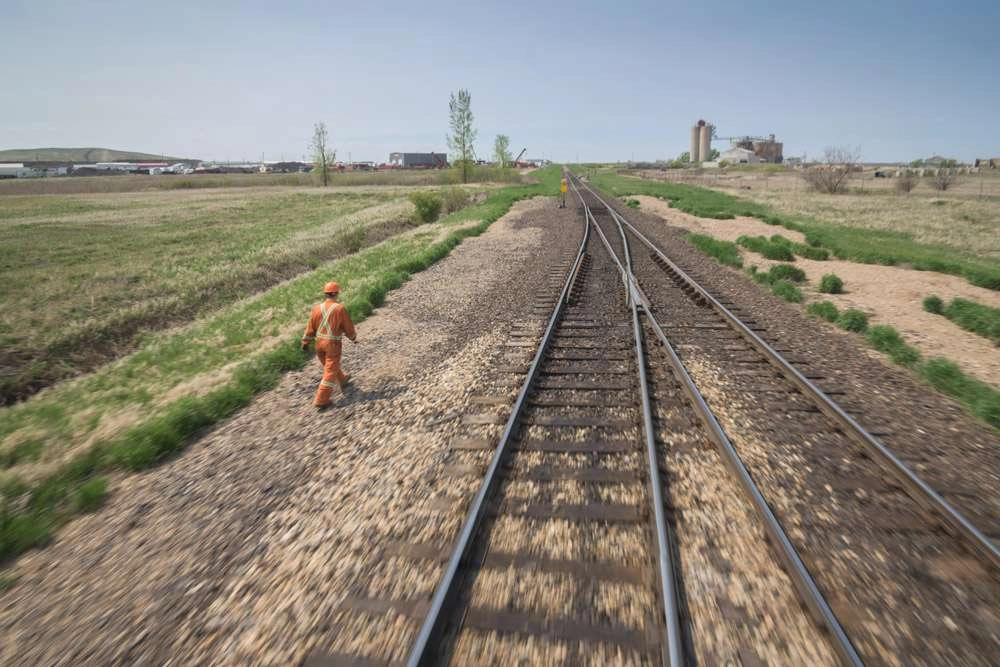 I wanted to create movement in this image of the worker walking beside the tracks. This was accomplished with a slower shutter speed, movement of the train and a large aperture. © robert lowdon