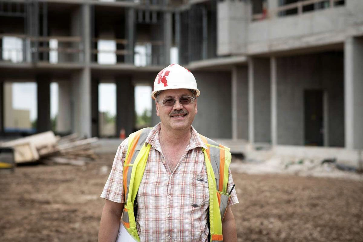 A worker smiles in front of the job site. © robert lowdon