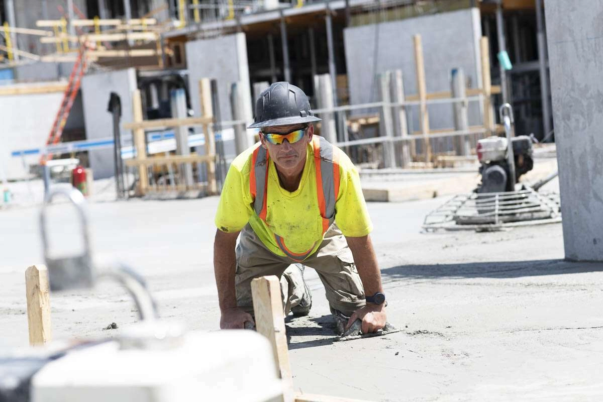 A concrete worker finishing the surface of a newly poured floor. © robert lowdon