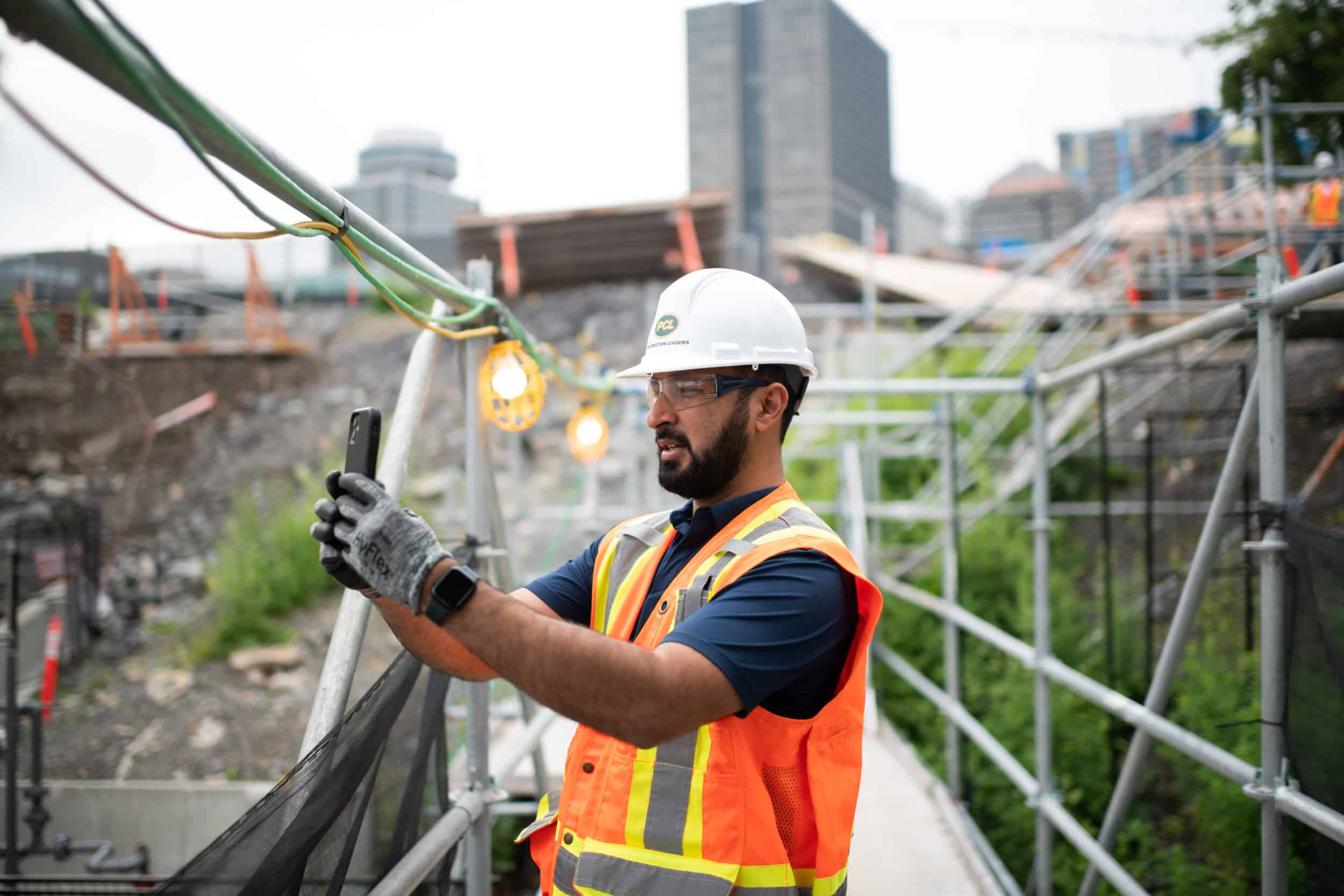 The worker is taking a picture of the construction site below.