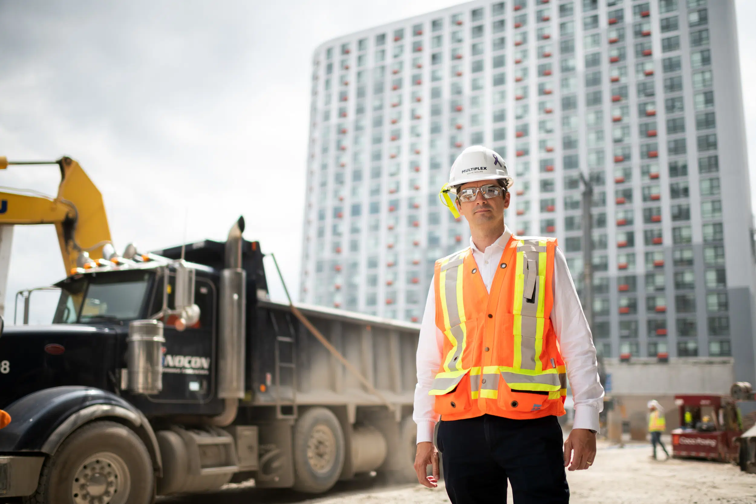 The construction executive is pictured on-site next to heavy construction equipment. This image could be used for a story about the executive's work in the construction industry, or for a story about the construction process itself.