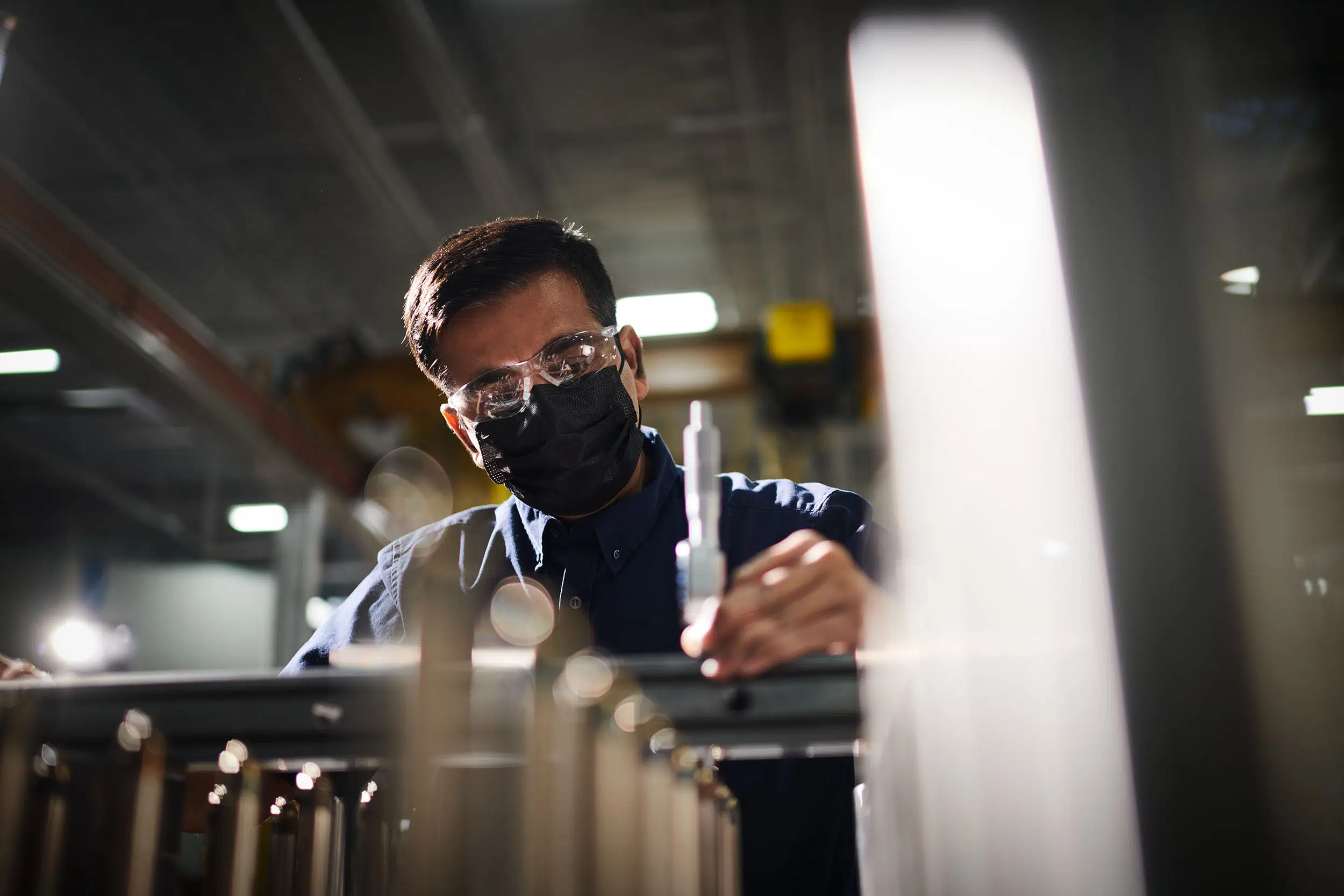A worker measures various parts of a manufactured item.