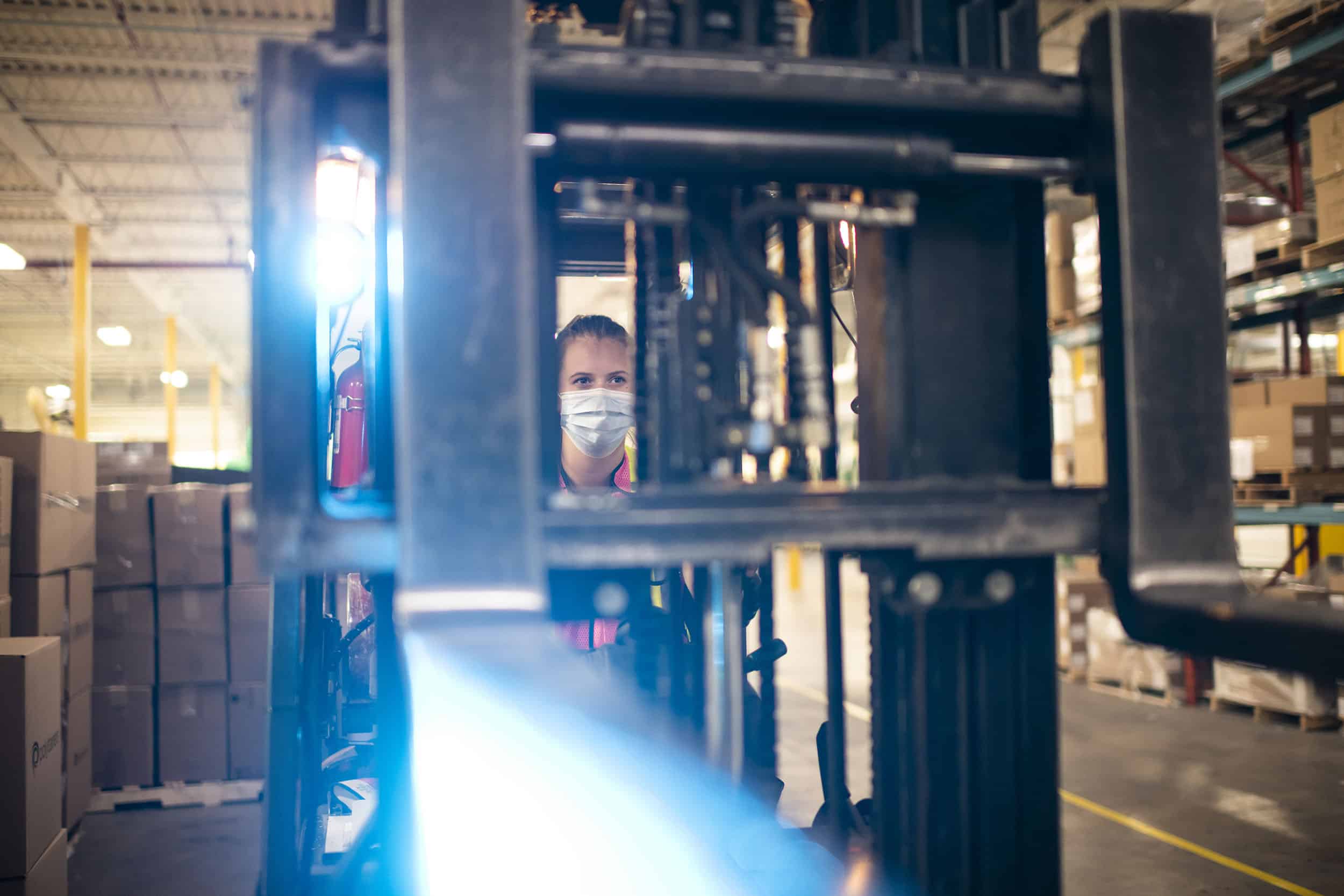 A female forklift operator picks up a pallet.