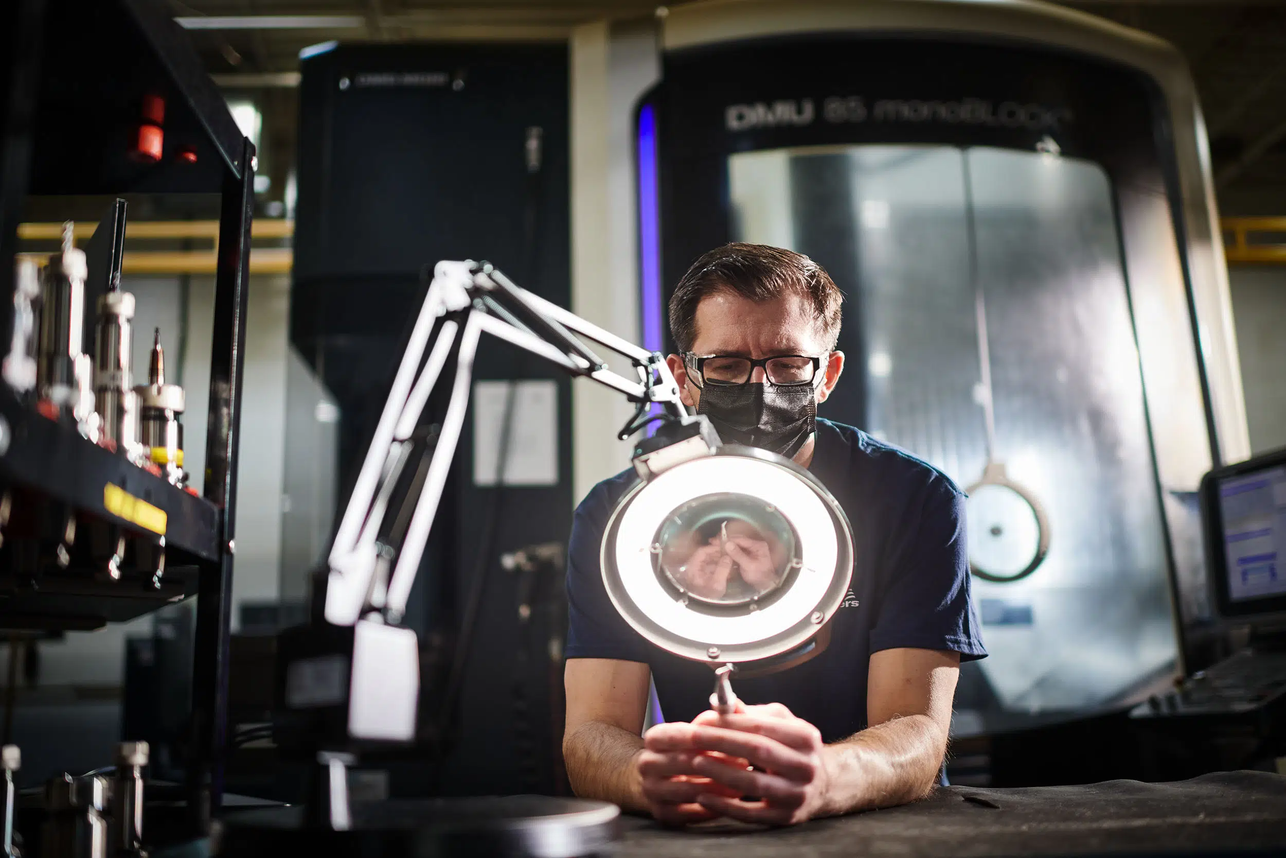 A worker inspects the fine details of a machined part.