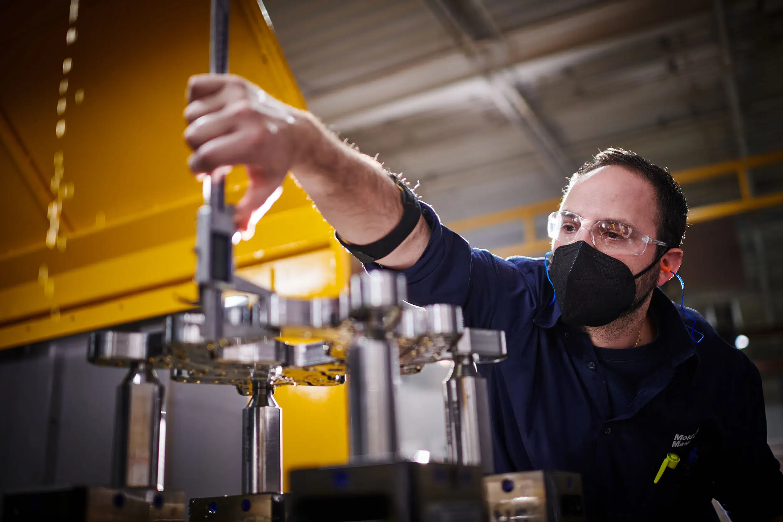 A worker uses a caliper to measure a finished cut.