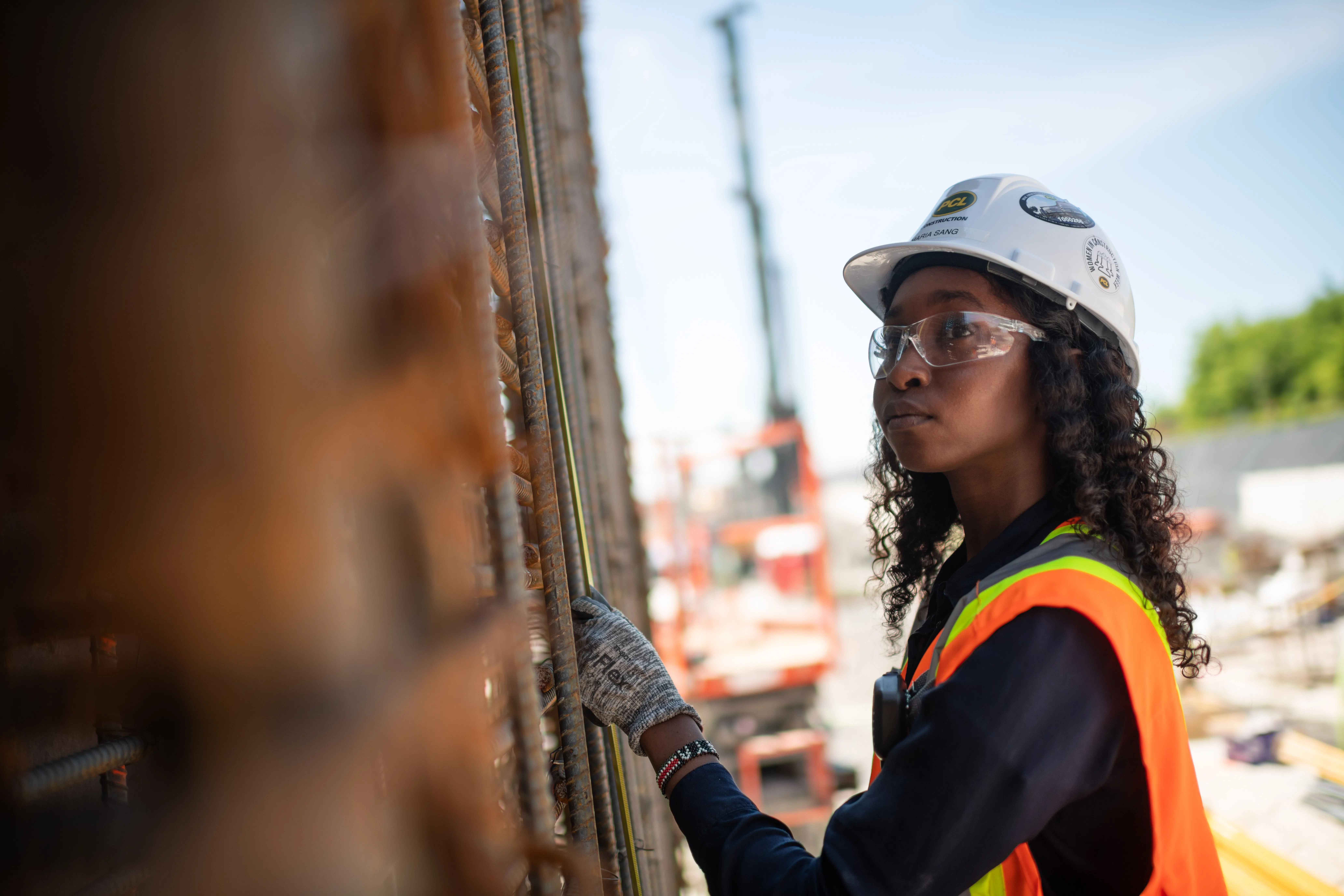 A construction worker inspects rebar for specifications.