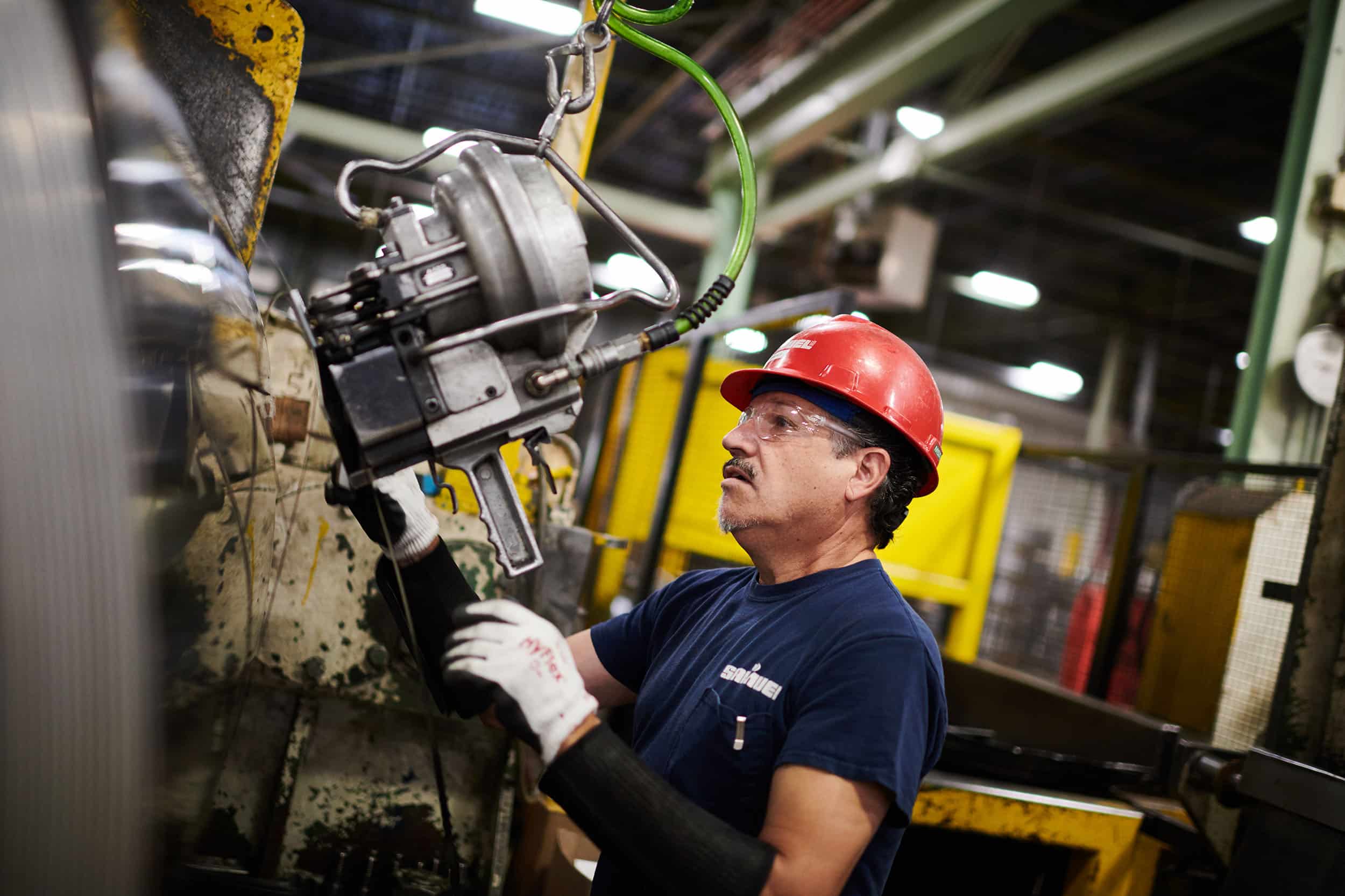 A worker binds a large roll of steel.