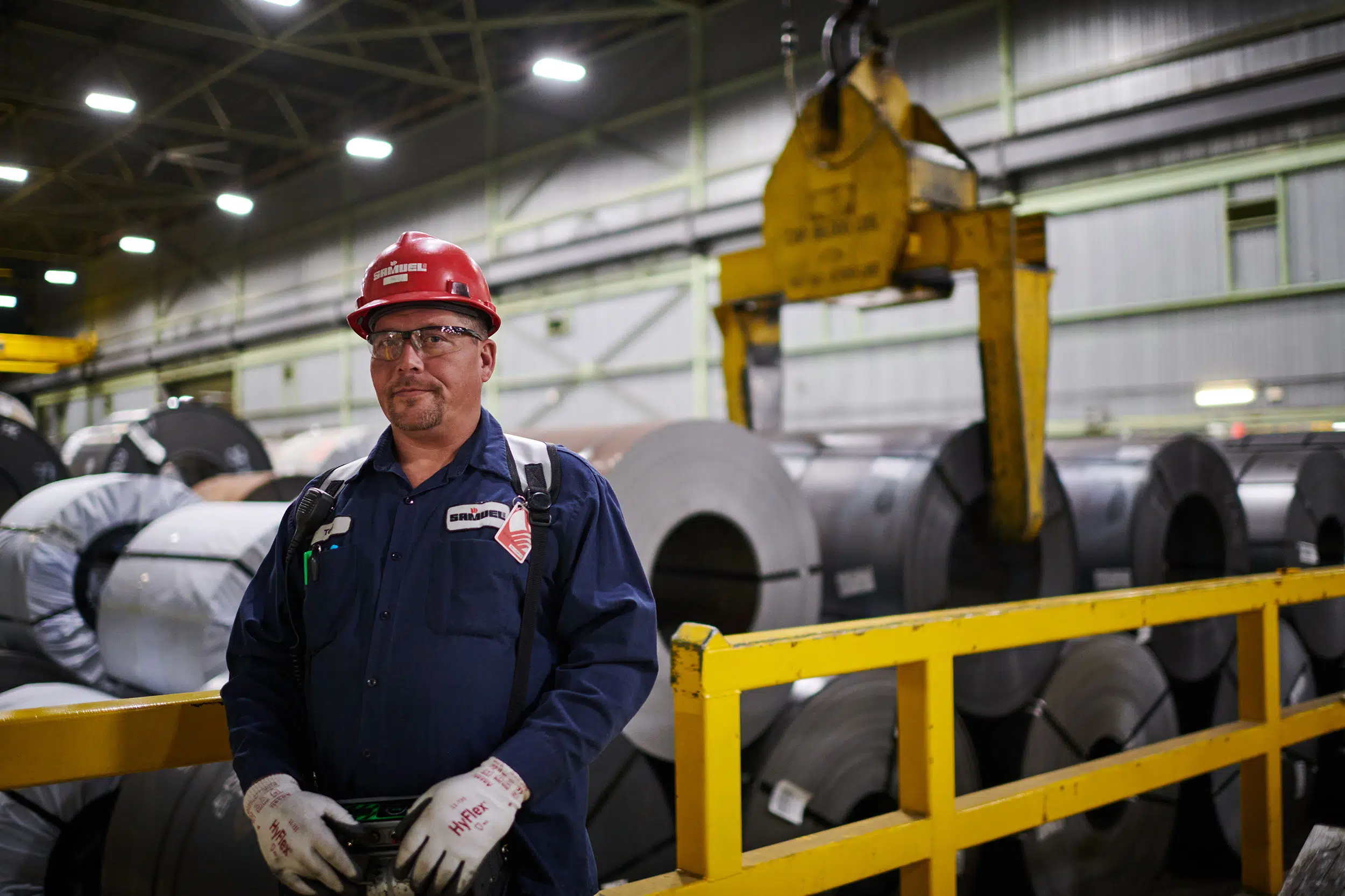 Worker by large rolls of steel.