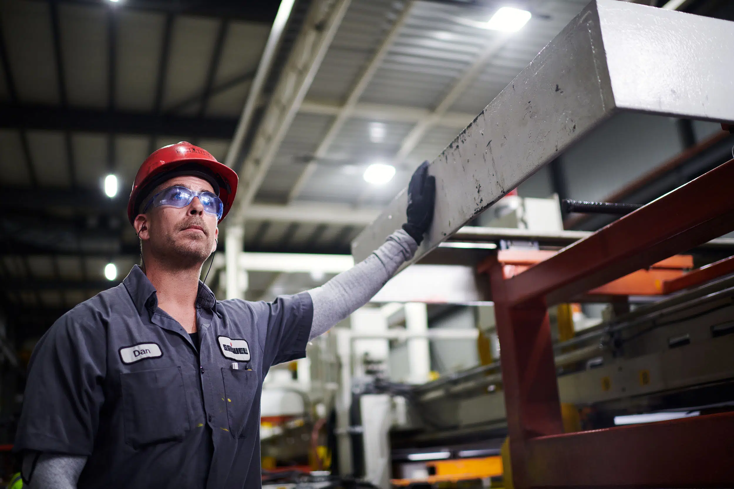 A worker leans on a machine while watching the production line.